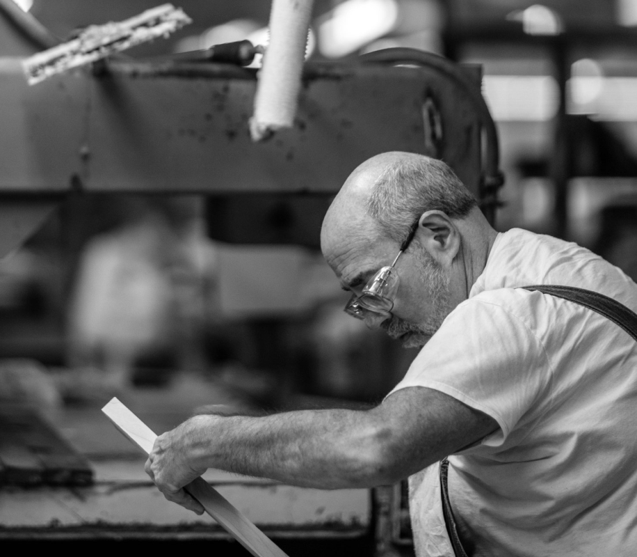 Black and white image of Bridgewood Cabinetry worker looking over wooden frame in woodworking shop