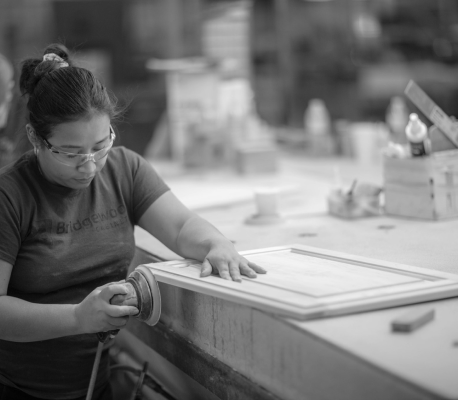 Bridgewood cabinetry employee using a sander on wooden door frame in woodworking shop