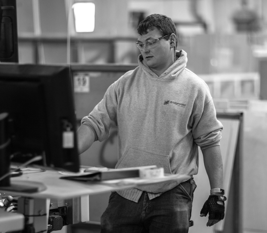 Black and white image of a Bridgewood Cabinetry worker looking at computer in woodworking shop