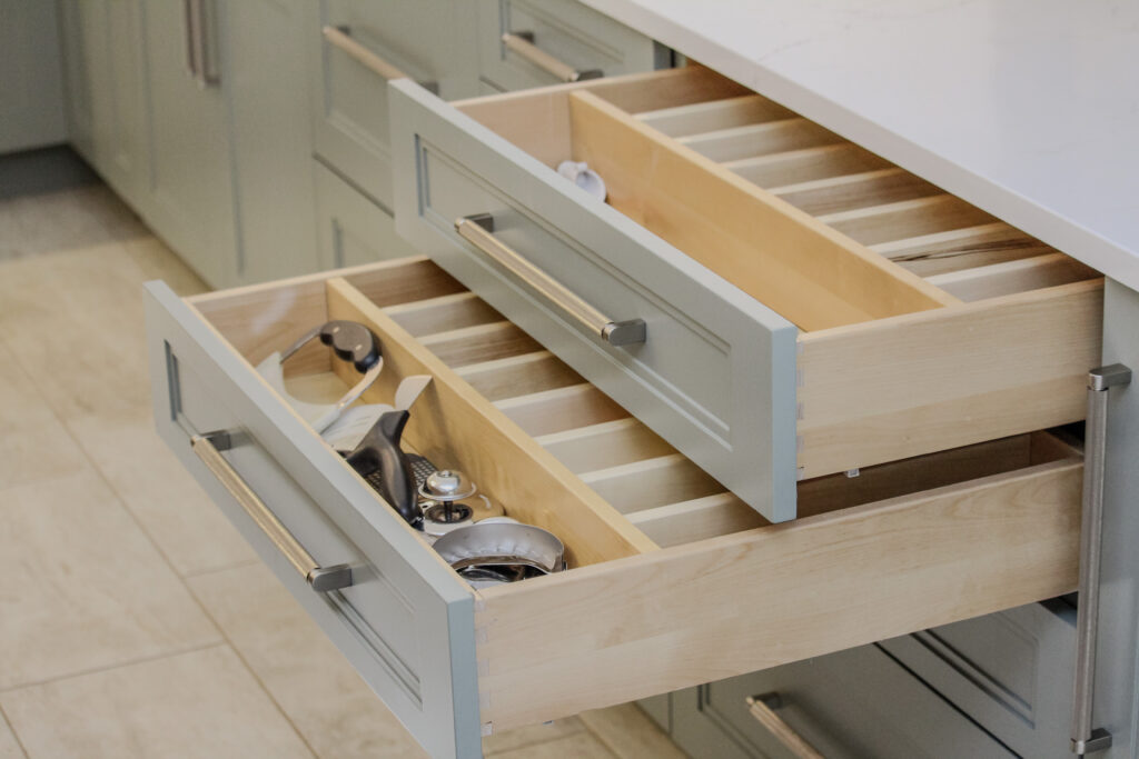 Painted maple kitchen drawers finished with acacia haze, with customized utensil drawer organizers.