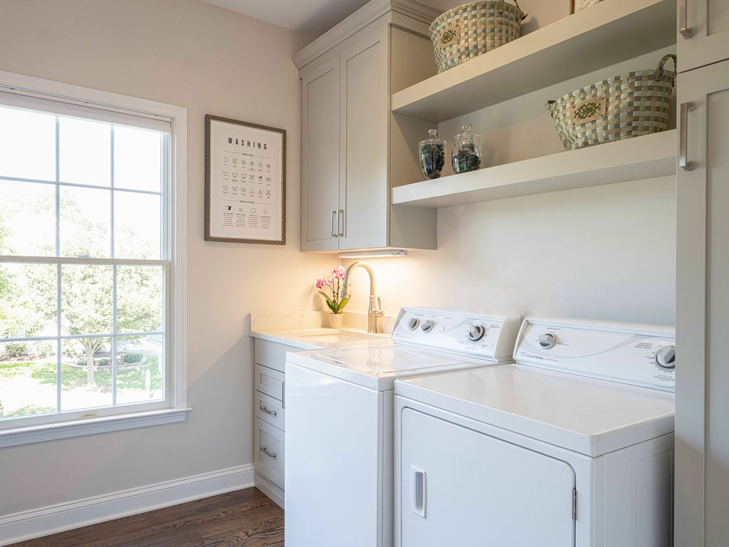 Custom cabinetry for laundry room featuring painted maple cabinets. Cabinets are painted in the Boulder finish with simple shaker door styles on upper and lower cabinets.